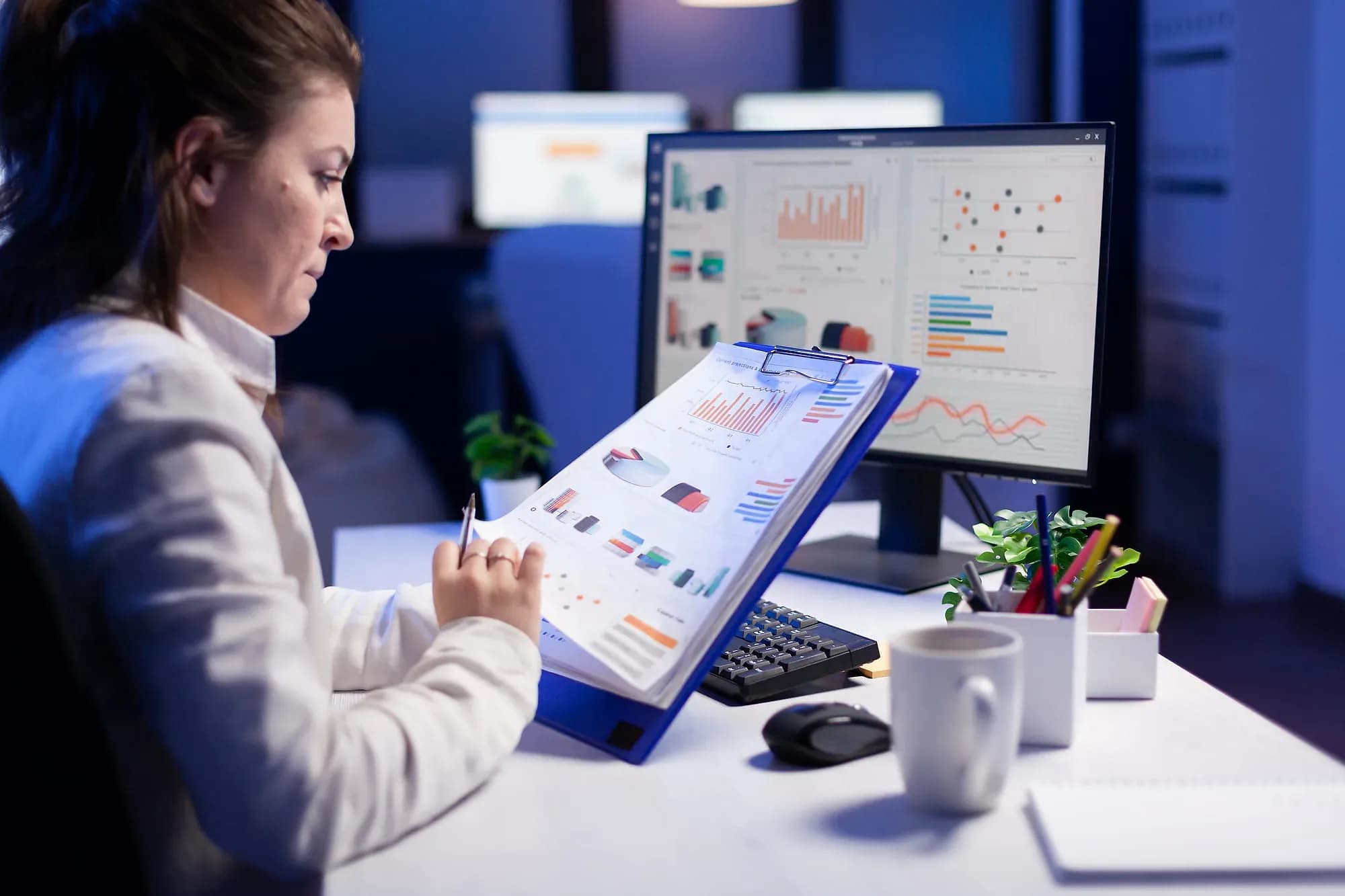 Operator reconciling printed shift reports against a live sales dashboard